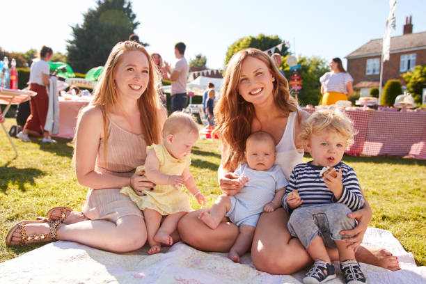 portrait of two mothers with children on rug at summer garden fete - family child crowd british culture imagens e fotografias de stock