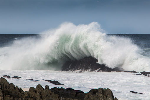 Wave crashing onto rock causing a big splash, action shot.