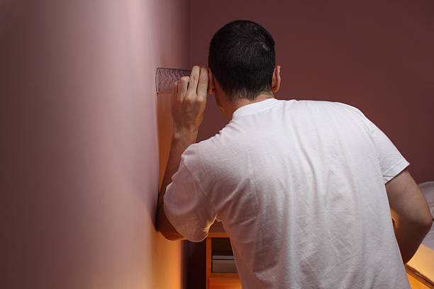 Eavesdropping Man eavesdropping through a bedroom wall using a glass eavesdropping stock pictures, royalty-free photos & images