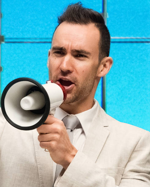 istock Handsome businessman standing at work and yelling into a megaphone 1048332184