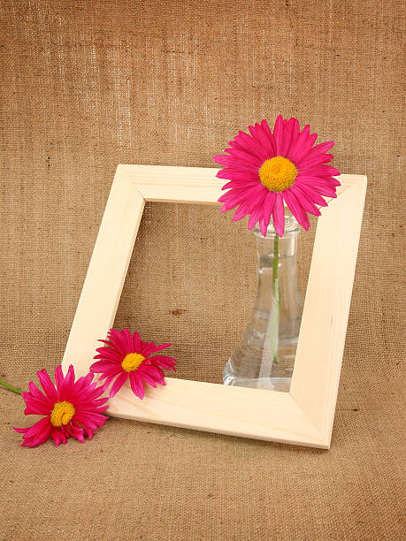 Wooden picture frame and daisy flowers in vase stock photo
