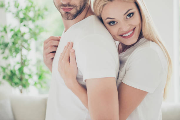 istock Side profile view portrait of beautiful attractive lovely charming cute nice affectionate stylish couple, bearded man, blonde girl in white t-shirts on at home, embracing, cuddling, light interior 1048345198