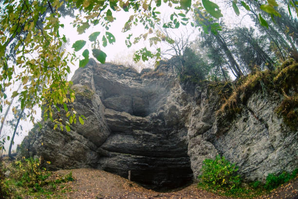 istock Autumn landscape: rocks in the forest, grotto, cave . Parking ancient man in the wild. 1048352736