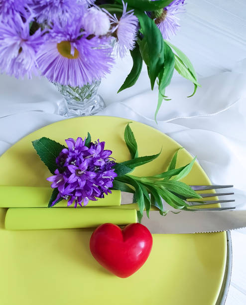istock plate, fork, knife, heart, chrysanthemum flower on a white wooden background 1048362830