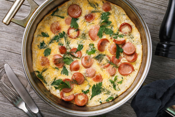 istock Scrambled eggs with sausage and greens in frying pan, top view, closeup 1048363806