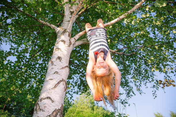 istock Happy girl hanging from a tree in a summer park 1048372024