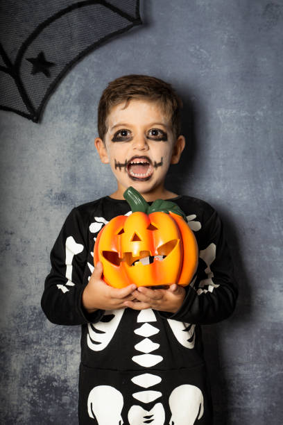 istock Young boy in the Skeleton costume holding Halloween pumpkin 1048372138