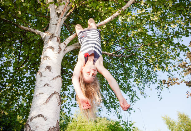 istock Happy girl hanging from a tree in a summer park 1048372420