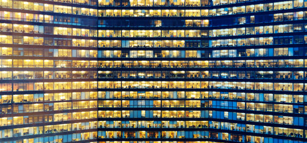 istock Sunset and dark sky reflecting in windows. Office workers working late in major office building 1048383530