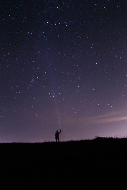 istock Man with a lantern under a starry night sky. Blue dark night sky with many stars. Milky way cosmos background. Night scape with beautiful starry sky. Space background 1048387986