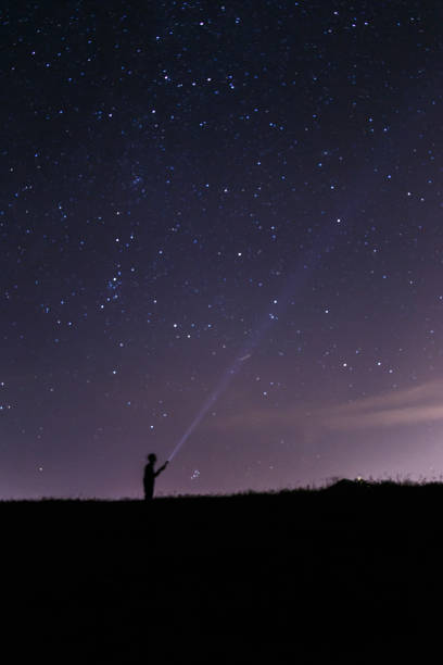 istock Man with a lantern under a starry night sky. Blue dark night sky with many stars. Milky way cosmos background. Night scape with beautiful starry sky. Space background 1048391004