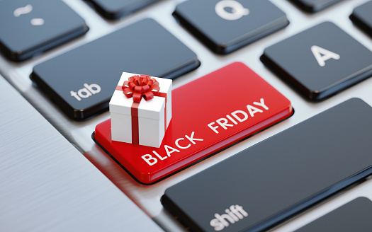 Modern computer keyboard with a white gift box and a red Black Friday button.  Horizontal composition with selective focus and copy space. Great use for shopping and Black Friday related concepts.