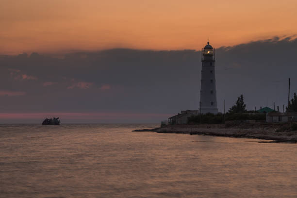 istock Lighthouse and sunken shipi in sea at sunset 1048402630
