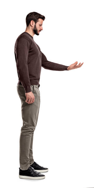 A bearded man in casual clothes stands still in a side view and looks down to his empty outstretched hand. A bearded man in casual clothes stands still in a side view and looks down to his empty outstretched hand. Invisible object. New invention. Showing new goods. male is standing and shows outstretched hand with open palm stock pictures, royalty-free photos & images
