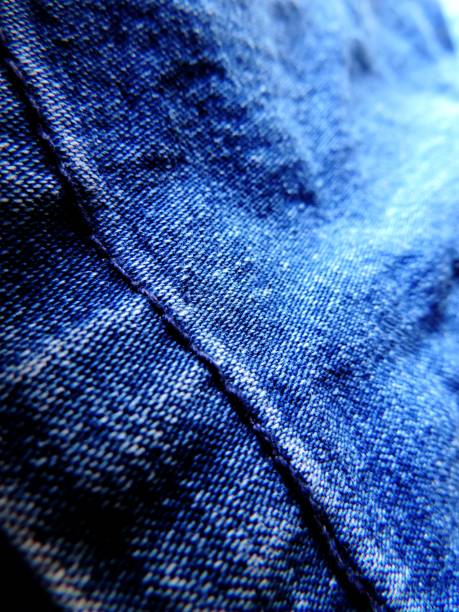 istock Close up image of vibrant blue textured denim jeans with hem with blue stitching 1048423062