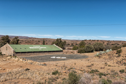 PHILLIPSTOWN, SOUTH AFRICA, AUGUST 6, 2018: A farm scene at Modderfontein near Phillipstown in the Northern Cape Province. A barn and the figure 200 are visible. Wind turbines are visible in the back