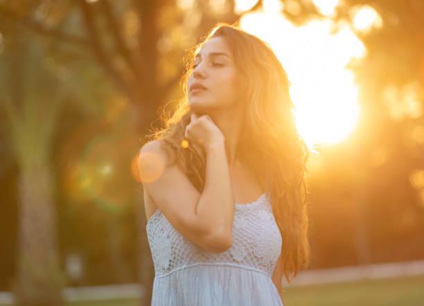 Beautiful young  woman looking at camera with sunset ,outside shot