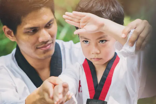 Photo of Taekwondo master black belt teaching kid to fight guard