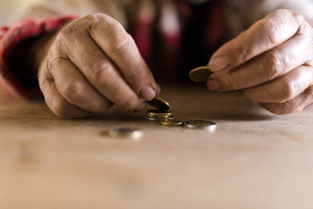 istock Man with dirty hands sitting at his desk counting coins 1048457284