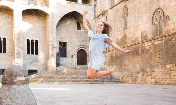 istock Girl jumping up against stone building 1048460804