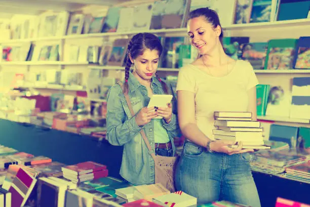 Female teenager is buying books and searching information on tablet.