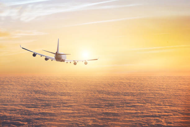 istock airplane flying above clouds in sunset sky 1048467010