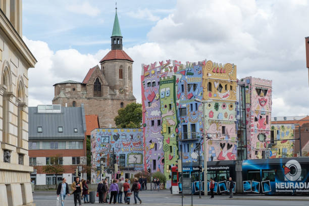 Happy Rizzi House and Saint Magni Church in Braunschweig, Germany Braunschweig, Germany – September 22, 2018: people wait for crossing at Happy Rizzi House; the Rizzi House was designed by the American artist James Rizzi (1950-2011) and implemented by Brunswick architect Konrad Kloster in 2001. braunschweig stock pictures, royalty-free photos & images