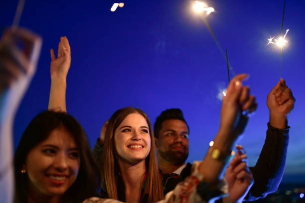 istock young people raising sparklers to blue night sky 1048483000