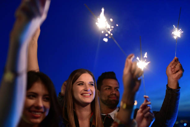 istock young people raising sparklers to blue night sky 1048483220
