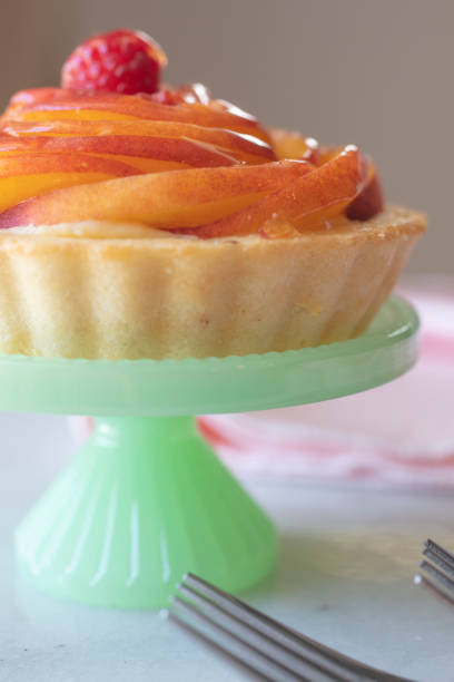 pfirsich puddingtörtchen auf einem grünen podest-teller - peach nectarine fruit portion stock-fotos und bilder