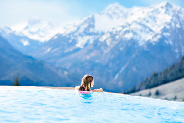 child in outdoor swimming pool of alpine resort - snow mountain austria winter imagens e fotografias de stock