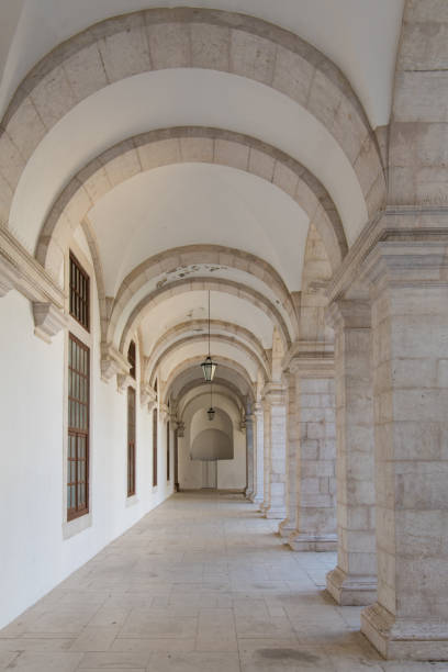 istock Long passageway moving to perspective under arches with stone block columns on one side and a white wall on the other side  - vertical orientation 1048500138