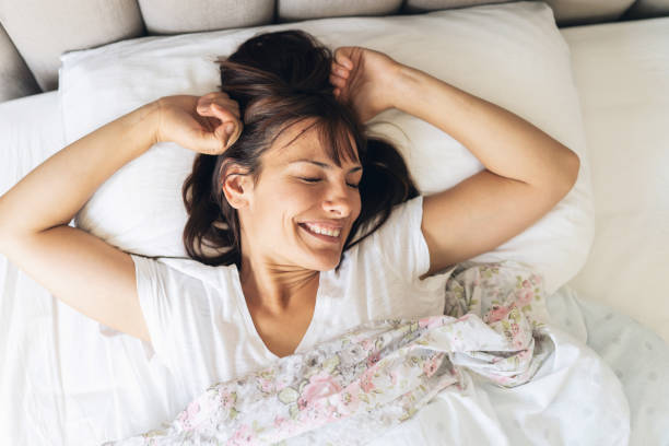istock Happy woman waking up in bed 1048500562