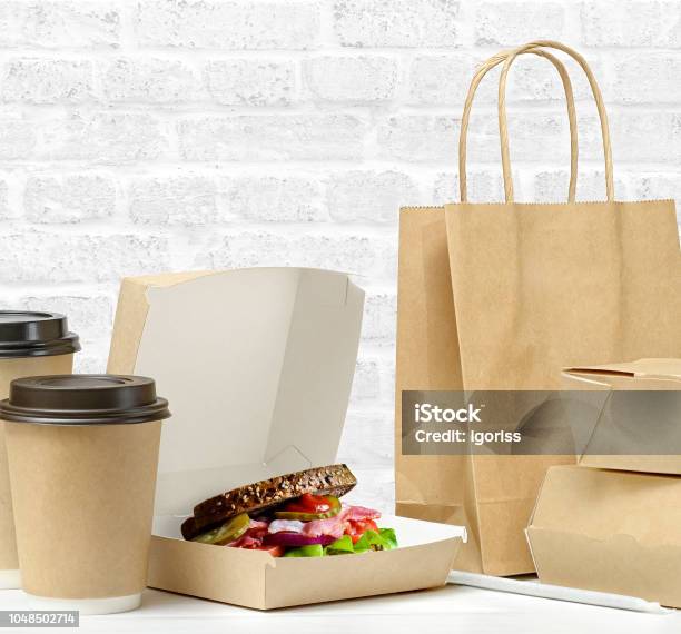Fast Food And Drink Packaging With Freshly Prepared Sandwich With Bacon Tomato Cucumber On Whole Grain Wheat Toast Stock Photo - Download Image Now