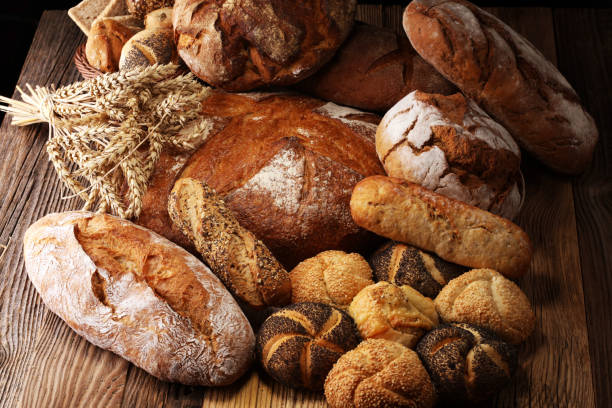 istock Different kinds of bread and bread rolls on board from above. Kitchen or bakery 1048519864