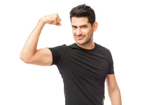 hombre joven atractivo vestido con camiseta negra mostrando sus bíceps - flexing muscles fotografías e imágenes de stock