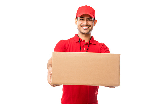 Handsome young man wearing red uniform delivering package over white background