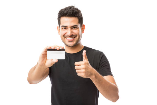 istock Smiling Young Man Holding Credit Card While Gesturing Thumbs Up 1048532268