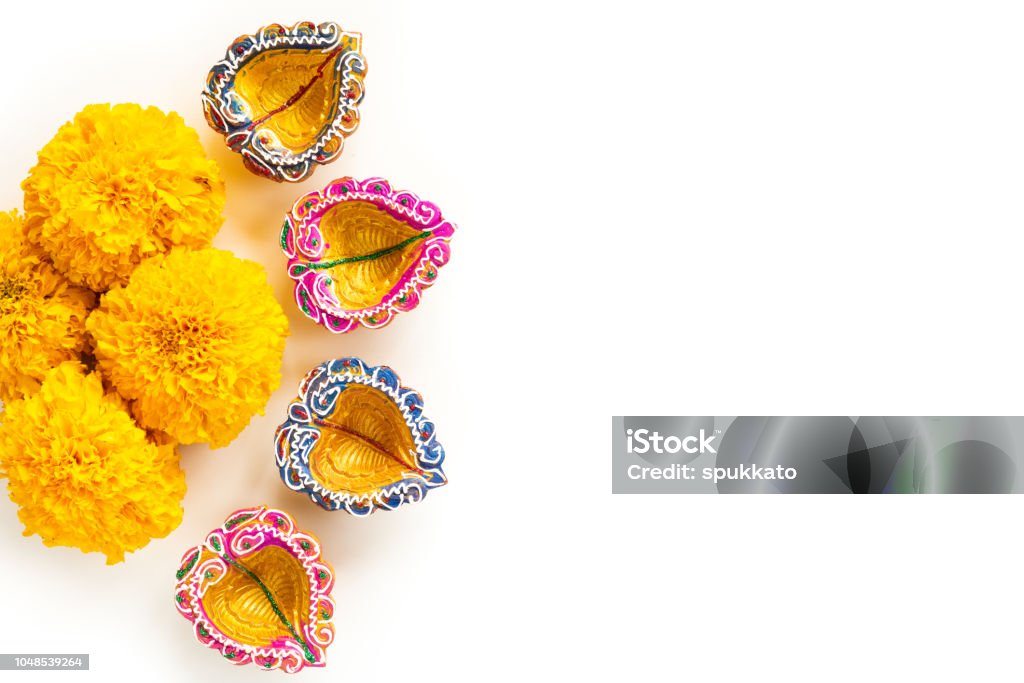 Happy Diwali - Clay Diya lamps lit during Dipavali, Hindu festival of lights celebration. Colorful traditional oil lamp diya with yellow flower on white background Diwali Stock Photo