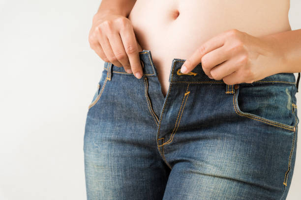 overweight fat woman wearing jeans. weight loss stomach closeup. skinny jeans on a healthy slim fit body. diet concept. - belly button imagens e fotografias de stock