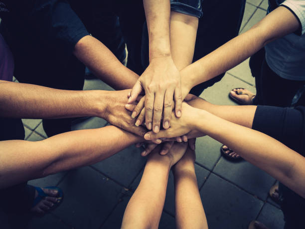 istock Teamwork concept; many people standing hands together in field before starting competition game 1048539394