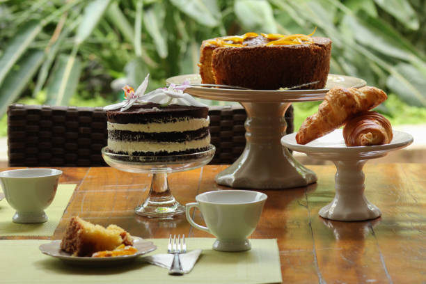 Beautiful breakfast table setting with orange cake, naked cake,  croissant with a nice garden view