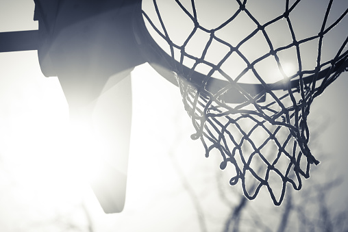 A close up of a basketball hoop with the sun shining through it.