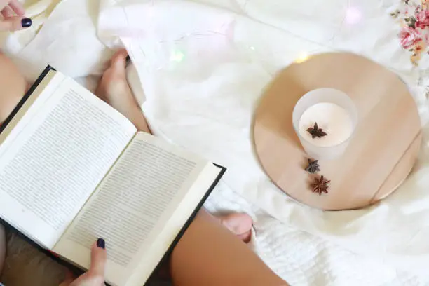Young woman in bed reading a book. Christmas. Fairy tale.