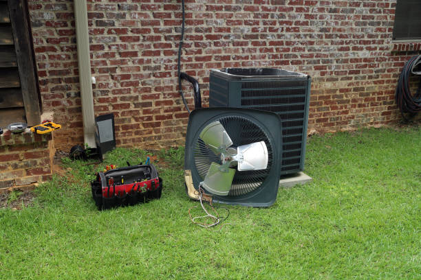 Air Conditioner Condenser coil with tools being repaired Air Conditioner compressor condenser coil with fan and tools being worked on next to a brick house for repair maintenance. air duct photos stock pictures, royalty-free photos & images