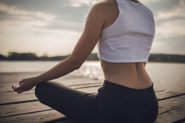 One woman, meditating by the lake outdoors alone.