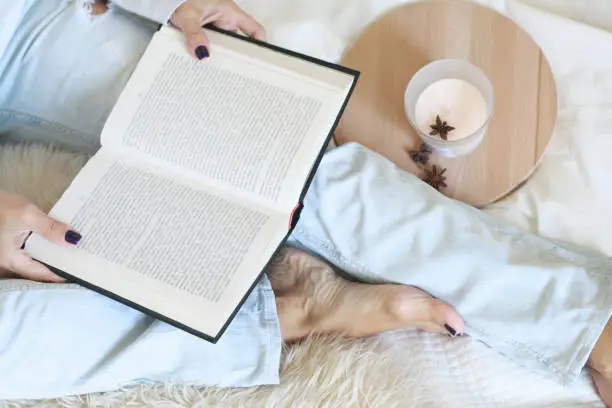 Young woman in bed reading a book