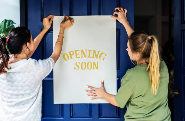 Women putting on store opening soon sign Women putting on store opening soon sign opening event stock pictures, royalty-free photos & images