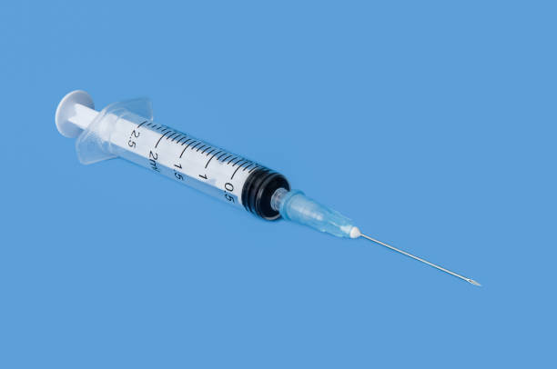 istock Transparent disposable syringe with needle on blue background. 1048624520