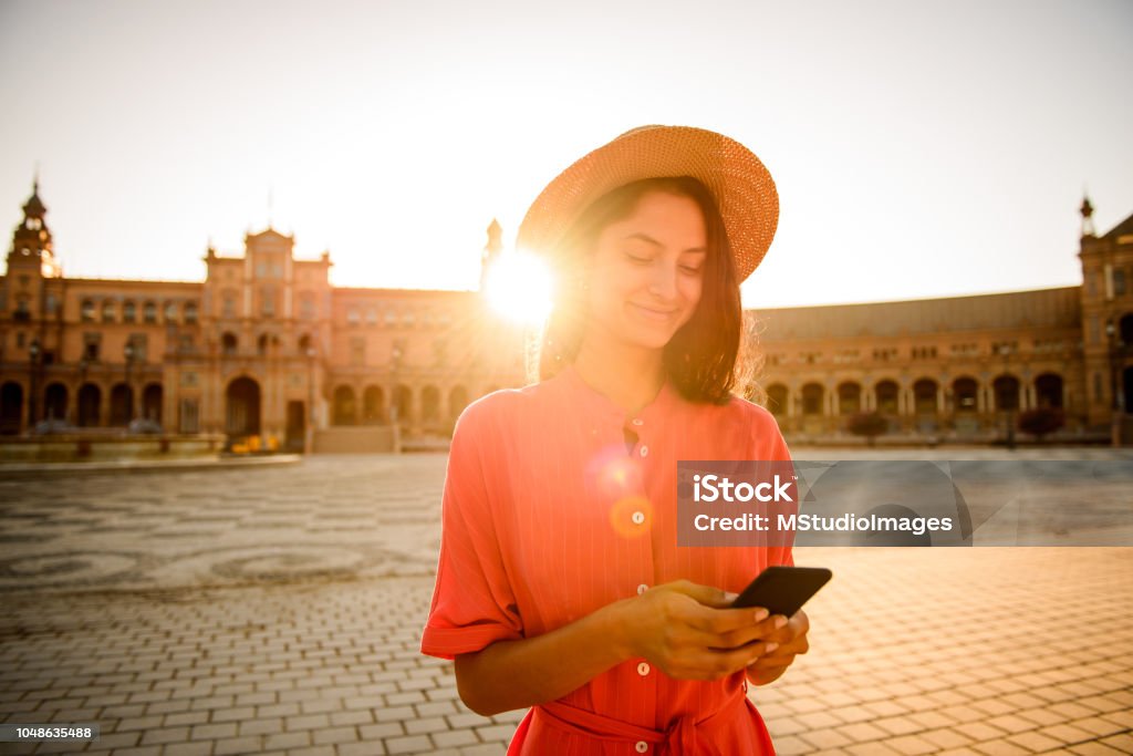 Using mobile phone. Elegant woman visiting Plaza de Espana, Sevilla Seville Stock Photo